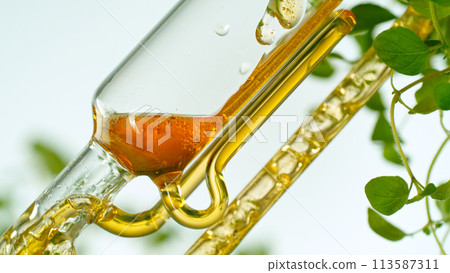 Getting essential oil from natural substances and flowers. Yellow oil flows in a spiral. 113587311