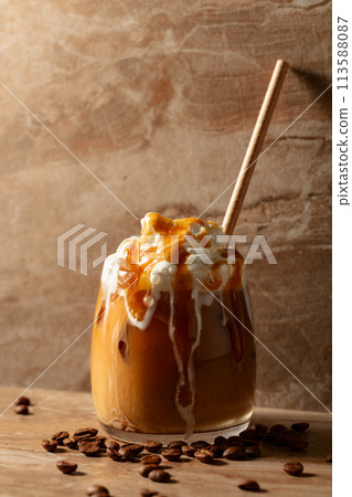 Iced caramel latte topped with whipped cream and caramel sauce. 113588087