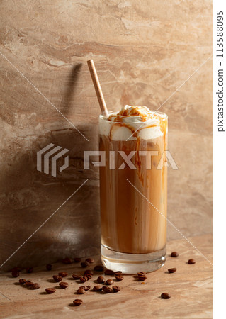 Iced caramel latte topped with whipped cream and caramel sauce. 113588095