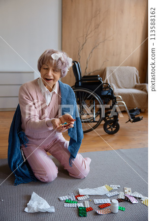 Old lady with dementia mental disorder eating pills scattered on floor 113588162