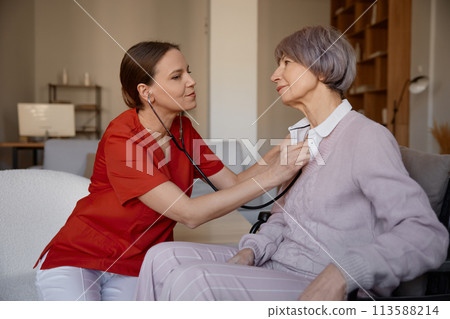 Woman doctor using stethoscope while examining senior woman at nursing home Woman doctor using stethoscope while examining senior woman at nursing home 113588214