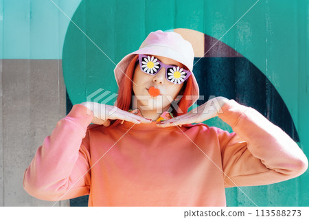 Woman with peach hair, bucket hat in sunglasses with flowers stickers and heart-shaped sticker on the lips. Makeup, cosmetics, artificial beauty, fashion doll concept. Vanilla Girl. Candy color design Woman with peach hair, bucket hat in sunglasses with flowers stickers and heart-shaped sticker on the lips. Makeup, cosmetics, artificial beauty, fashion doll concept. Vanilla Girl. Candy color design 113588273