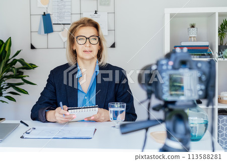 50's confident mature businesswoman, middle-aged experienced senior female professional recording video vlog webinar, online course. Female edtech entrepreneur shares skills, blogger online business 113588281