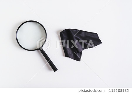 Magnifier for magnification in black plastic frame and cleaning cloth on blue background top view Magnifier for magnification in black plastic frame and cleaning cloth on blue background top view 113588385