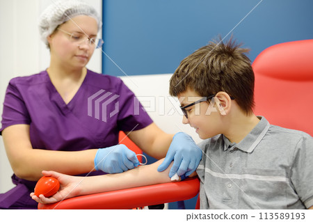 A nurse takes blood from a child using butterfly needle. Close up view during of taking a blood sample for examination in a modern laboratory or hospital. A nurse takes blood from a child using butterfly needle. Close up view during of taking a blood sample for examination in a modern laboratory or hospital. 113589193