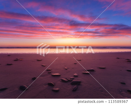 Seascape during sunrise. Bright clouds on the sky. Lines of sand on the seashore. Seascape during sunrise. Bright clouds on the sky. Lines of sand on the seashore. 113589367
