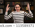 Portrait of an angry woman boss with glasses in the office looks at the camera and screams 113589371