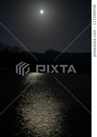 Moon age 18.2 The moon is setting in the west, and the moon's path is reflected on the surface of an irrigation pond. 113589456