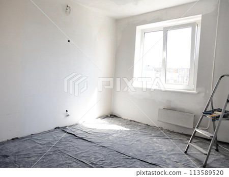 Room renovation, a ladder and a roller for painting walls. The concept of repair in the house. Room renovation, a ladder and a roller for painting walls. The concept of repair in the house. 113589520