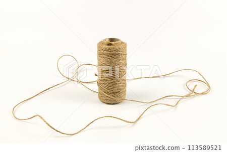 A spool of linen rope on a white background. The concept of textiles and sewing. A spool of linen rope on a white background. The concept of textiles and sewing. 113589521
