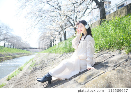 A woman listening to music under the cherry blossoms A woman listening to music under the cherry blossoms 113589657