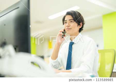 一個年輕的商人在辦公室打電話 113589985