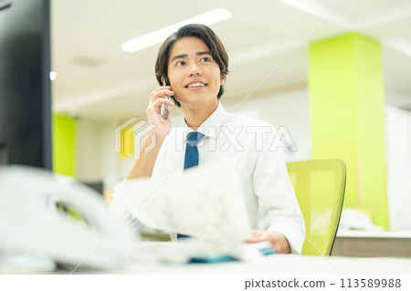 一個年輕的商人在辦公室打電話 113589988
