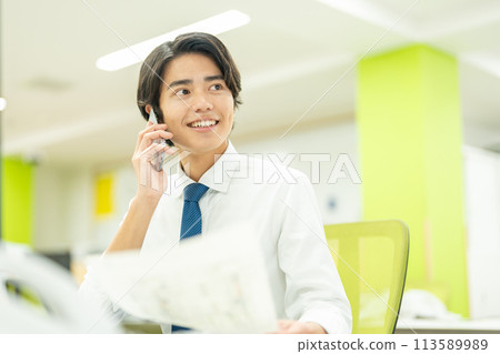 一個年輕的商人在辦公室打電話 113589989