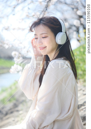 A woman listening to music under the cherry blossoms 113590108