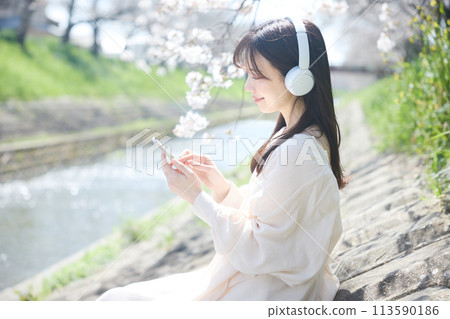 A woman listening to music under the cherry blossoms A woman listening to music under the cherry blossoms 113590186