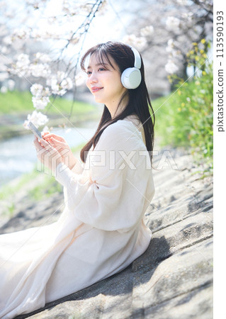 A woman listening to music under the cherry blossoms 113590193