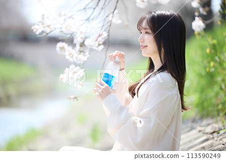 A woman drinking a soft drink under the cherry blossoms A woman drinking a soft drink under the cherry blossoms 113590249
