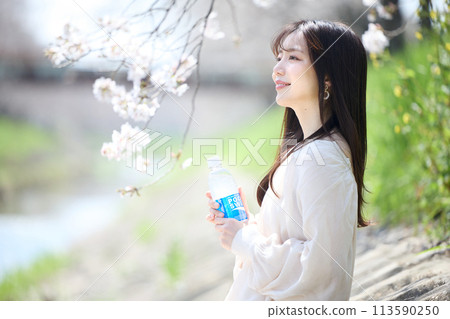 A woman drinking a soft drink under the cherry blossoms A woman drinking a soft drink under the cherry blossoms 113590250