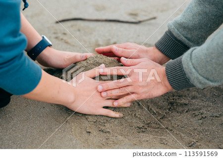 一對夫婦的雙手在沙箱中建造一座山 113591569