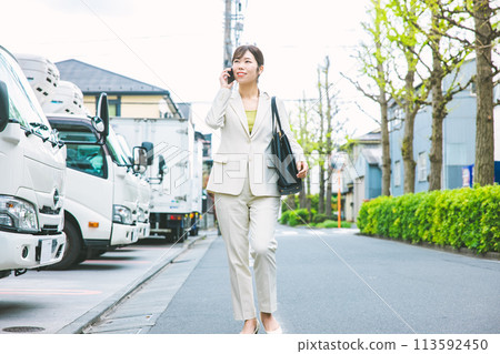 Businesswoman walking while talking on her smartphone Businesswoman walking while talking on her smartphone 113592450