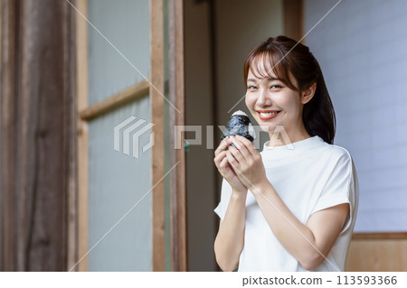 A cute woman eating rice balls on the veranda A cute woman eating rice balls on the veranda 113593366
