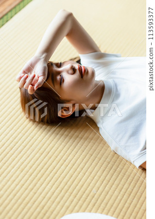 A woman lying down on a tatami mat to cool off A woman lying down on a tatami mat to cool off 113593377