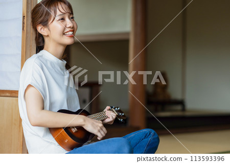 A woman practicing the ukulele on the veranda A woman practicing the ukulele on the veranda 113593396