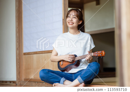 A woman practicing the ukulele on the veranda 113593710