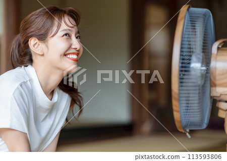 Cute woman cooling off with an electric fan Cute woman cooling off with an electric fan 113593806