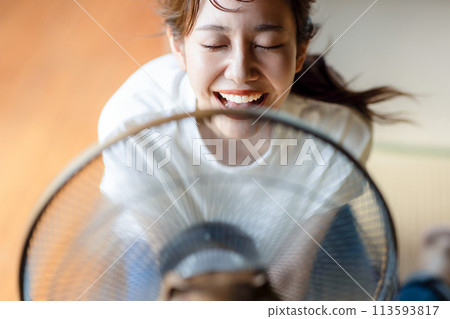 Cute woman cooling off with an electric fan 113593817
