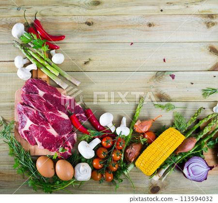 Raw beef with fresh vegetables on wooden background 113594032