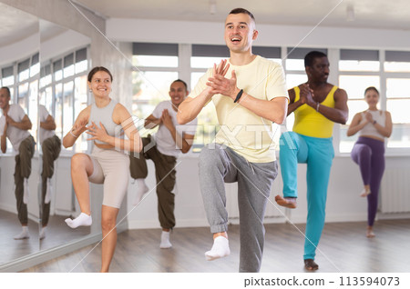 Guy and group of young active multinational people dancing Hip-hop dance or brakedance in dance hall 113594073