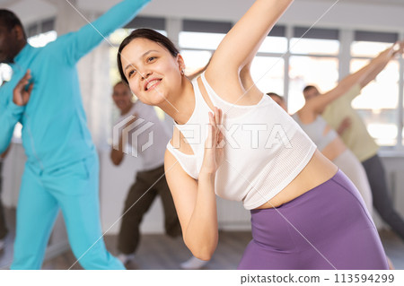 Happy multinational man and girl dancing rock and roll dance in dance studio during group class Happy multinational man and girl dancing rock and roll dance in dance studio during group class 113594299