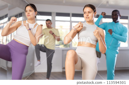 Girl practices kicking and punching in process of self-defense at group lesson Girl practices kicking and punching in process of self-defense at group lesson 113594301