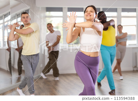 Active multinational men and women of different ages practicing Hip-hop dance in training hall during dancing classes 113594388