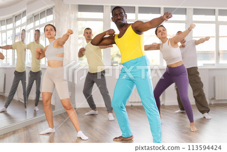 African man practices kicking and punching in process of self-defense at group lesson African man practices kicking and punching in process of self-defense at group lesson 113594424
