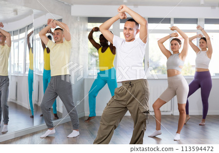 Group of multinational sports people rehearsing social dance in dance hall 113594472