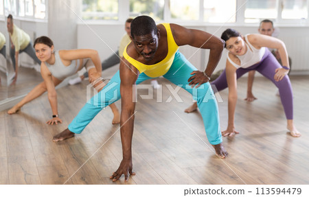 Group of sports multinational people practicing synchronous group choreography in dance studio Group of sports multinational people practicing synchronous group choreography in dance studio 113594479