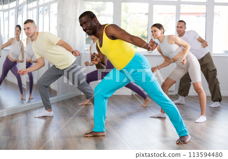 Happy African american man and group of international dancers training before big performance in dance class Happy African american man and group of international dancers training before big performance in dance class 113594480
