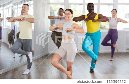 Emotional attractive young girl learning movements of traditional Caucasian dance lezginka during group training for adults in dance hall Emotional attractive young girl learning movements of traditional Caucasian dance lezginka during group training for adults in dance hall 113594532