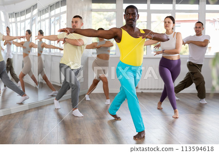 Enthusiastic black man energizing group during dance fitness class 113594618