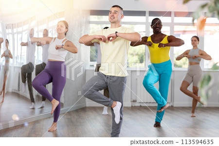 Group of multiethnic active people dancing and learning movements of traditional Caucasian dance lezginka in studio Group of multiethnic active people dancing and learning movements of traditional Caucasian dance lezginka in studio 113594635