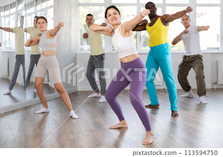 Asian girl practices kicking and punching in process of self-defense at group lesson Asian girl practices kicking and punching in process of self-defense at group lesson 113594750