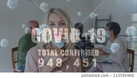 Covid-19 text with increasing cases against portrait of caucasian woman removing her face mask 113595468