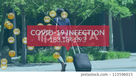 Image of covid 19 infection numbers end emojis over woman with suitcase wearing face mask Image of covid 19 infection numbers end emojis over woman with suitcase wearing face mask 113596015