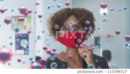 Image of covid 19 cells over woman in office wearing face mask 113596517