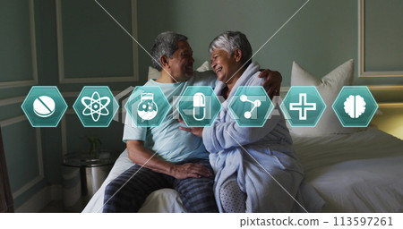 Multiple medical icons against african american senior couple laughing while sitting on bed Multiple medical icons against african american senior couple laughing while sitting on bed 113597261