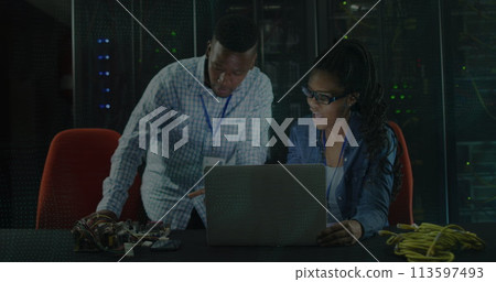 Image of digital chain over african american couple using laptop in server room 113597493
