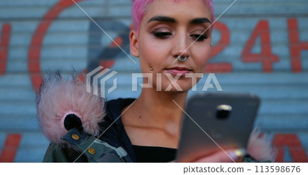 Young Caucasian woman checks her phone outdoors, with copy space 113598676